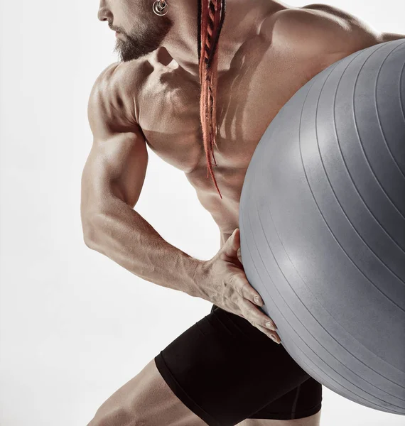 Hombre musculoso sosteniendo la pelota de fitness, de pie aislado en blanco — Foto de Stock