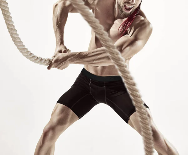 Attraktiver muskulöser Mann, der mit schweren Seilen trainiert. — Stockfoto