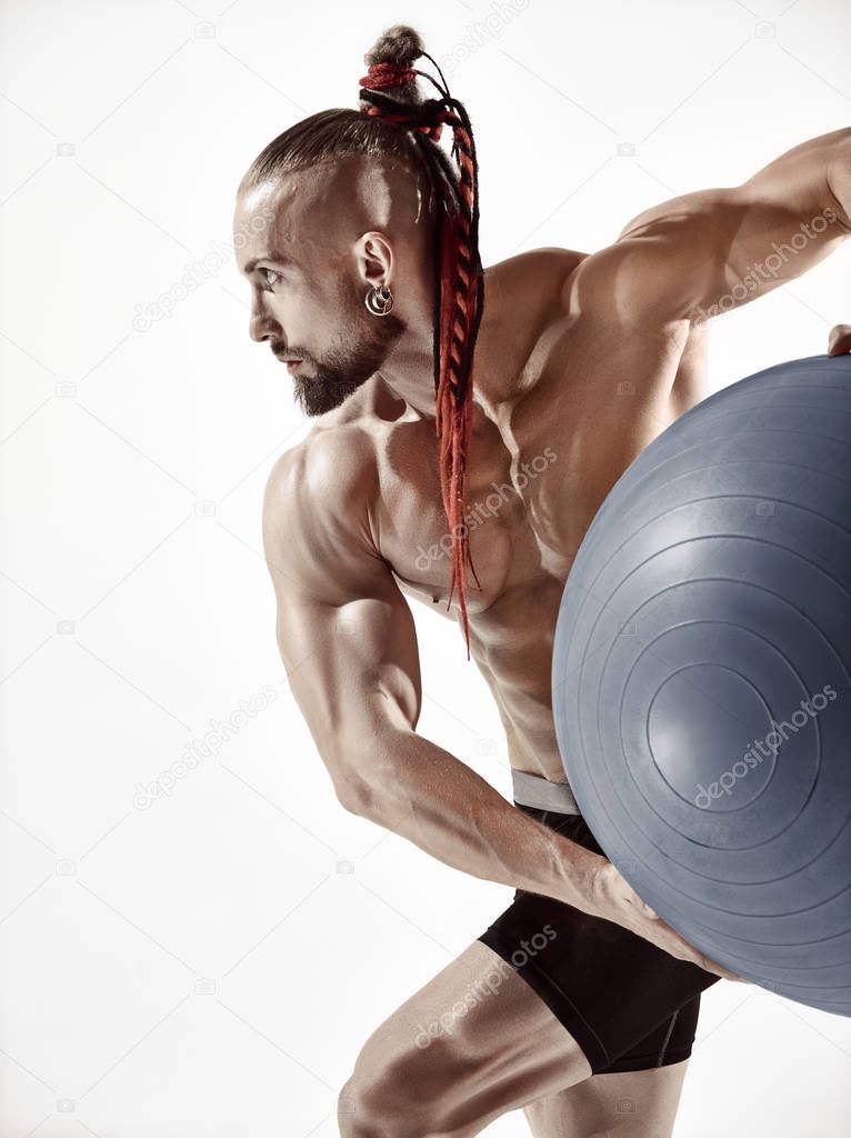 Muscular man holding fitness ball, standing isolated on white