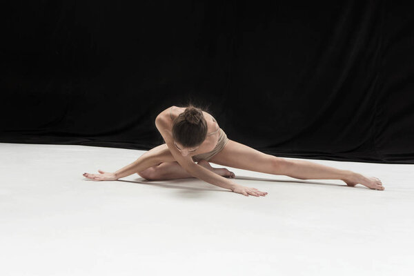 Young teen dancer dancing on white floor studio background. Ballerina project.