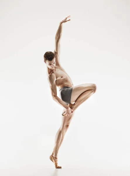 Bailarina de ballet atlética em uma forma perfeita realizando sobre o fundo cinza . — Fotografia de Stock