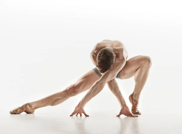 Bailarina de ballet atlética em uma forma perfeita realizando sobre o fundo cinza . — Fotografia de Stock