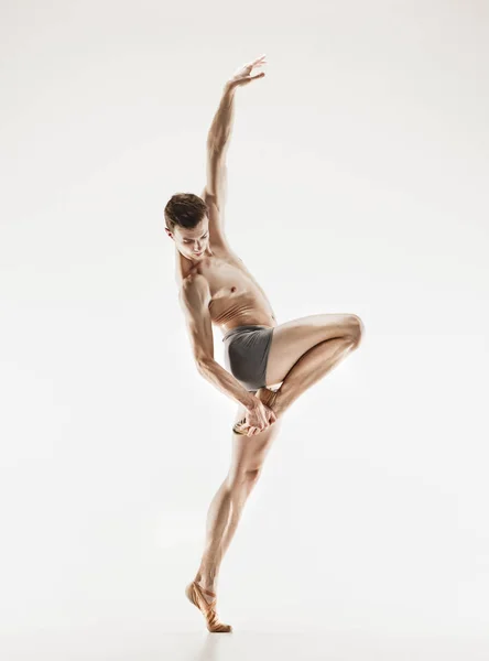 Athletische Balletttänzerin in perfekter Form, die vor grauem Hintergrund auftritt. — Stockfoto