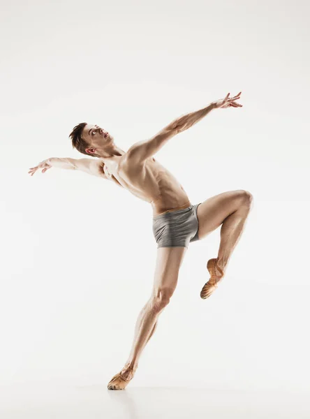 Bailarina de ballet atlética em uma forma perfeita realizando sobre o fundo cinza . — Fotografia de Stock