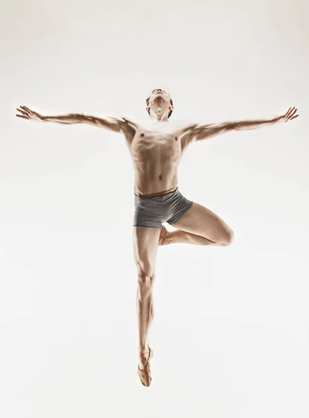 Bailarina de ballet atlética em uma forma perfeita realizando sobre o fundo cinza . — Fotografia de Stock