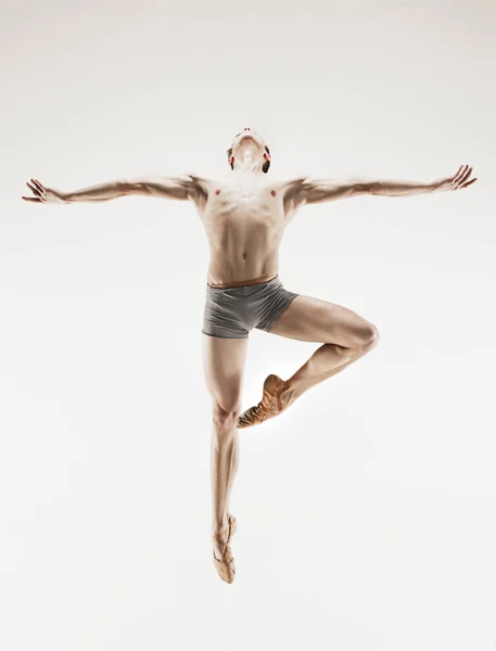 Bailarina de ballet atlética em uma forma perfeita realizando sobre o fundo cinza . — Fotografia de Stock