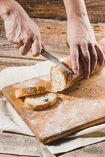 Whole grain bread put on kitchen wood plate with a chef holding gold knife for cut. — Stock Photo, Image