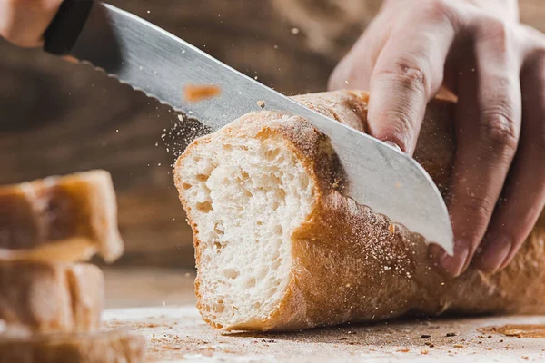 Pan de grano entero puesto en placa de madera de cocina con un chef sosteniendo un cuchillo de oro para cortar . —  Fotos de Stock
