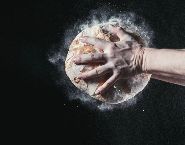 Fechar as mãos masculinas colocar pão fresco no fundo preto com espaço de cópia para o seu texto — Fotografia de Stock