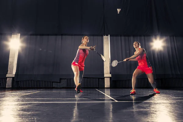 Unge kvinner som spiller badminton i gymsalen – stockfoto