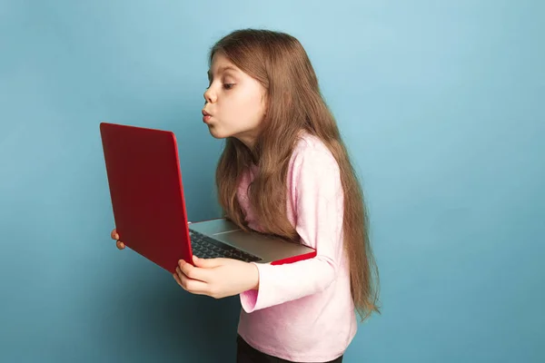 El amor de la computadora. Chica adolescente con cuaderno sobre un fondo azul. Expresiones faciales y personas concepto de emociones — Foto de Stock