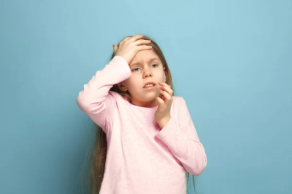 Huvudvärk. Teen flicka på en blå bakgrund. Ansikts uttryck och människor känslor koncept — Stockfoto