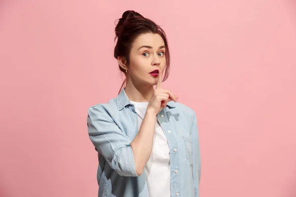 The young woman whispering a secret behind her hand over pink background — Stock Photo, Image