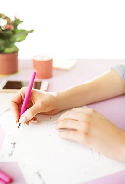 Το θηλυκό τα χέρια εκμετάλλευση στυλό. Το τηλέφωνο σε μοντέρνα ροζ γραφείο. — Φωτογραφία Αρχείου
