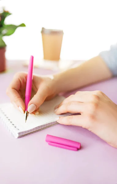 Ženské ruce drží pero. Telefon na stole módní růžové. — Stock fotografie