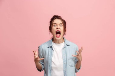 The young emotional angry woman screaming on pink studio background clipart