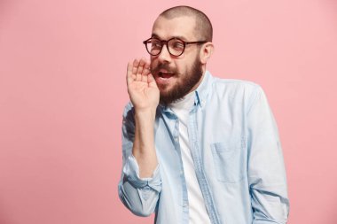 Pembe arka plan üzerinde elini arkasındaki sır fısıldayan genç adam