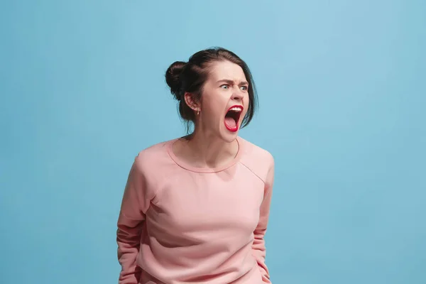 ブルー スタジオの背景に叫んで若い感情的な怒っている女性 — ストック写真