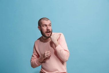 Mavi arka plan üzerinde elini arkasındaki sır fısıldayan genç adam