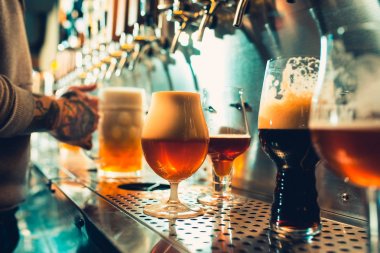 Oktoberfest karşılaştık. Barmen büyük lager bira dokunun içinde dökme el. İstemci için bira döküyor. Yan genç barmen barda bira dururken dökme görünümünü sayaç