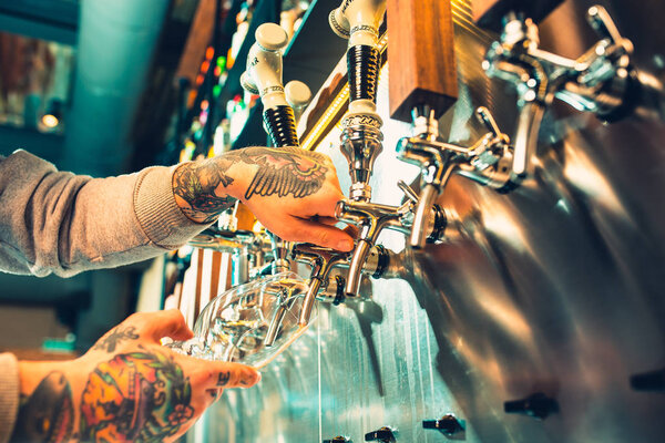 Hand of bartender pouring a large lager beer in tap.