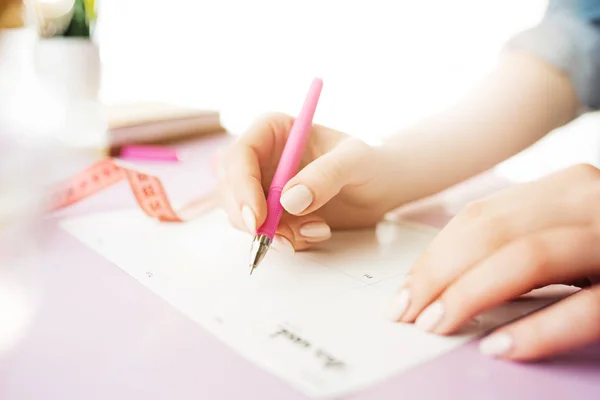 女性の手がペンを持ちます。トレンディなピンク デスク. — ストック写真