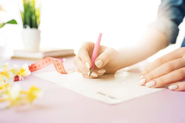 女性の手がペンを持ちます。トレンディなピンク デスク. — ストック写真
