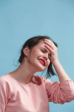 Baş ağrısı olan bir kadın. Mavi arka plan üzerinde izole.