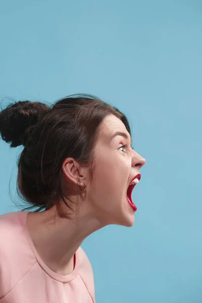 La joven mujer enojada emocional gritando en el fondo del estudio azul —  Fotos de Stock