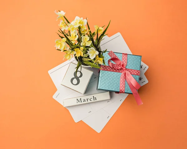 La vue du dessus du bureau orange avec cadeau, fleurs et cahier — Photo