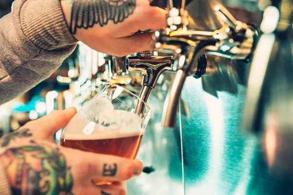Main de barman versant une grande bière lager dans le robinet . — Photo