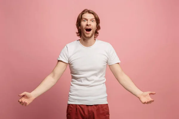 O jovem homem atraente olhando surpreendido isolado em rosa — Fotografia de Stock