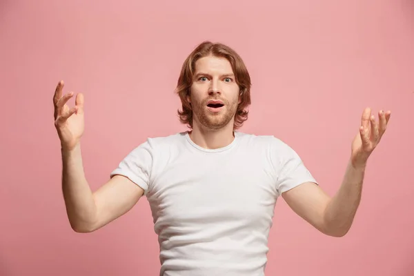 De jonge, aantrekkelijke man op zoek verrast geïsoleerd op roze — Stockfoto