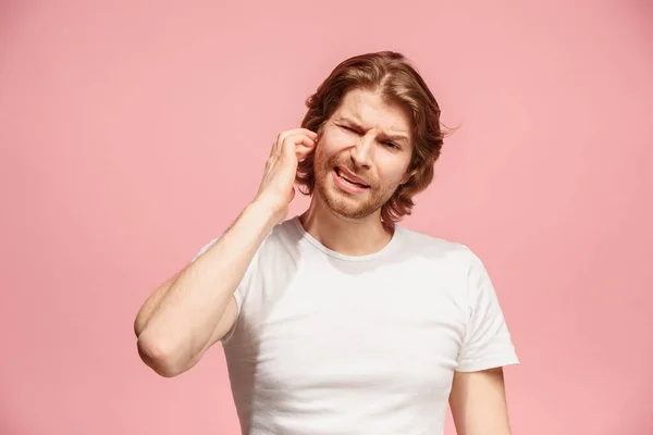 Il mal d'orecchio. L'uomo triste con mal di testa o dolore su uno sfondo studio rosa . — Foto Stock