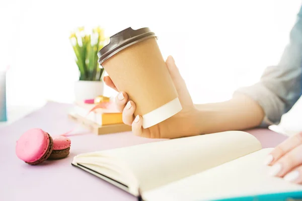 The female hands holding coffee. The trendy pink desk. — Stock Photo, Image