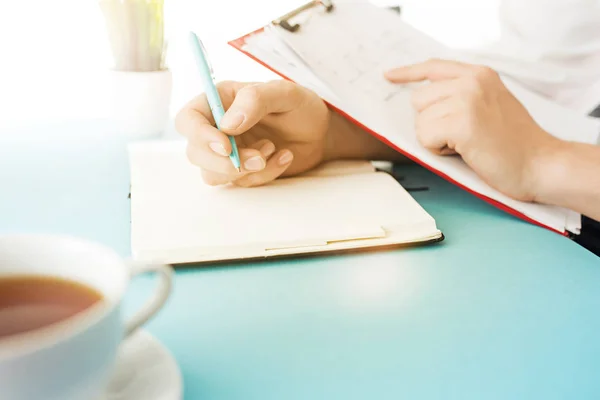 Las manos masculinas sosteniendo la pluma. El moderno escritorio azul . — Foto de Stock