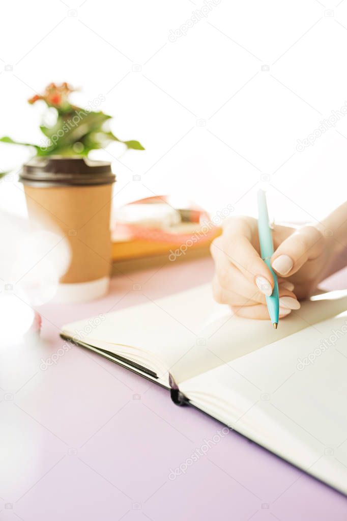 The female hands holding pen. The trendy pink desk.