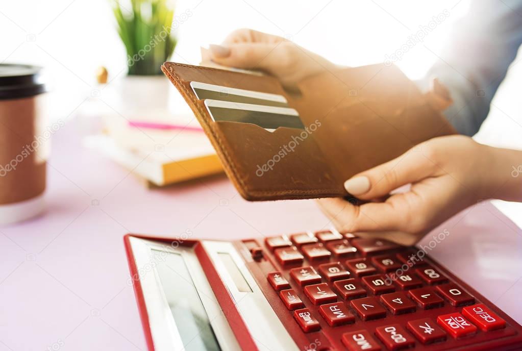 woman is holding purse, credit card in hands and calculating the costs