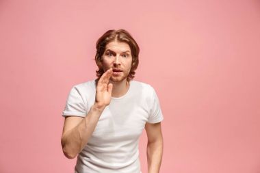 Pembe arka plan üzerinde elini arkasındaki sır fısıldayan genç adam