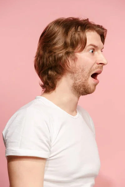 Der junge attraktive Mann sieht überrascht isoliert auf rosa — Stockfoto