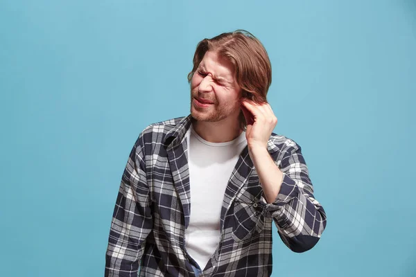 De oor-ache. De trieste man met hoofdpijn of pijn op een blauwe studio achtergrond. — Stockfoto