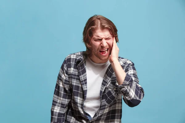 Ухо болит. Грустный человек с головной болью или болью на синем фоне студии . — стоковое фото