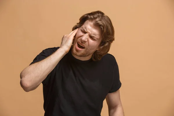 The Ear ache. The sad man with headache or pain on a pastel studio background.