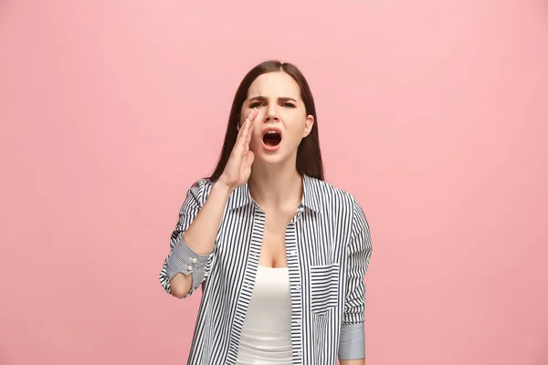 Mladá emocionální naštvaná žena křičí na růžové studio pozadí — Stock fotografie
