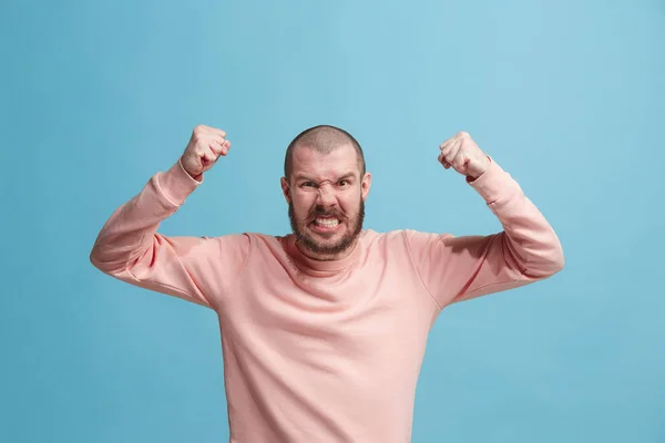 O jovem homem irritado emocional gritando no fundo do estúdio azul — Fotografia de Stock