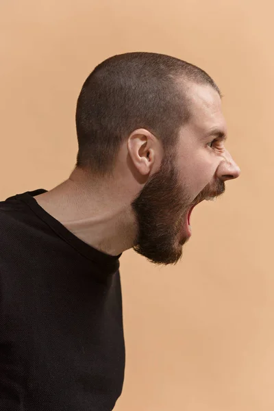 El joven hombre enojado emocional gritando en fondo de estudio pastel — Foto de Stock