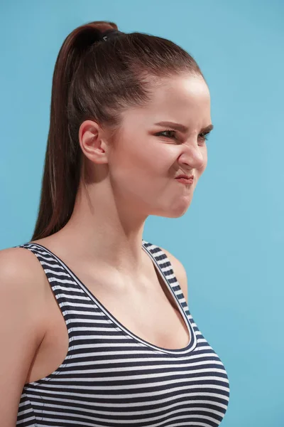 The young woman is looking angry on the blue background. — Stock Photo, Image