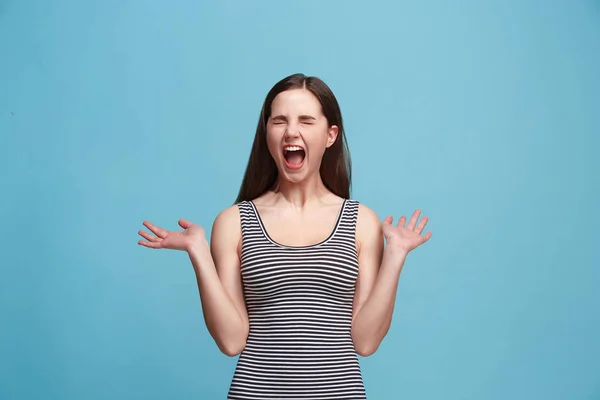 Молода емоційна розлючена жінка кричить на синьому студійному фоні — стокове фото