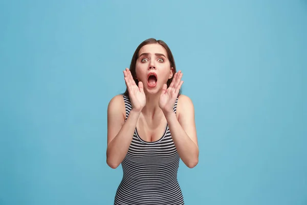 Изолированная на голубой молодой неформальной женщине, кричащей в студии — стоковое фото