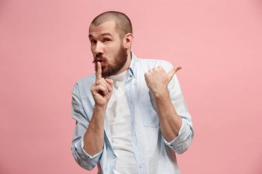 Pembe arka plan üzerinde elini arkasındaki sır fısıldayan genç adam